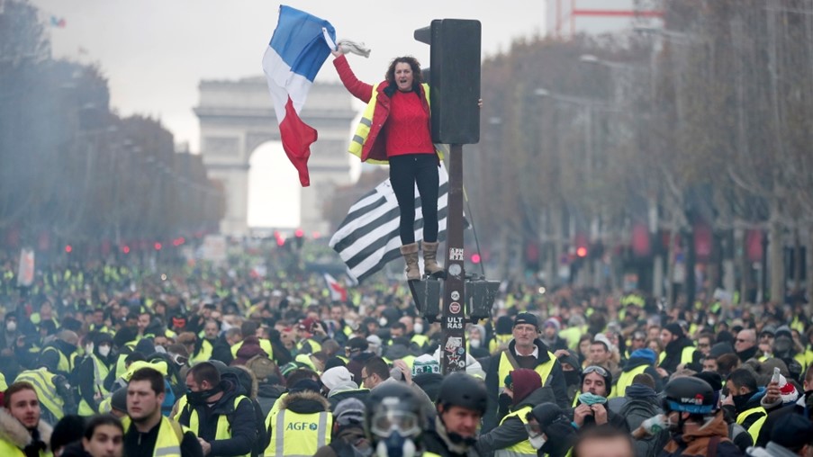 people protesting in a street in France wearing Yellow Vests